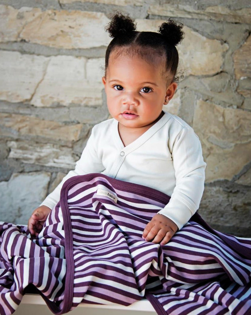 Child wearing Organic Swaddling Blanket in Eggplant Stripe.