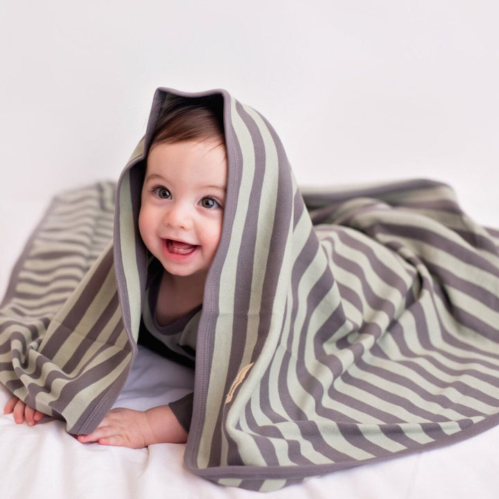 Child wearing Organic Swaddling Blanket in Gray/Seafoam Stripe.