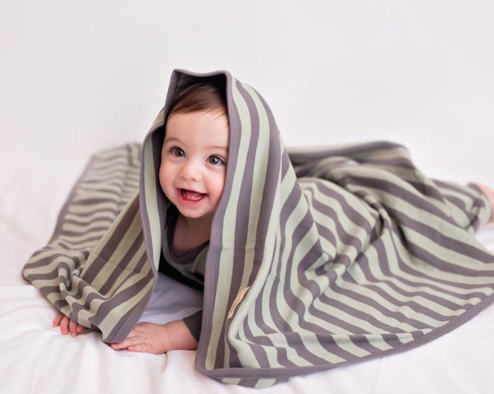 Child wearing Organic Swaddling Blanket in Gray/Seafoam Stripe.