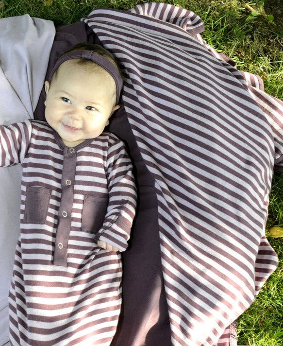 Child wearing Organic Swaddling Blanket in Lavender/Eggplant.