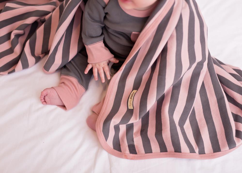 Child wearing Organic Swaddling Blanket in Mauve/Gray Stripe.