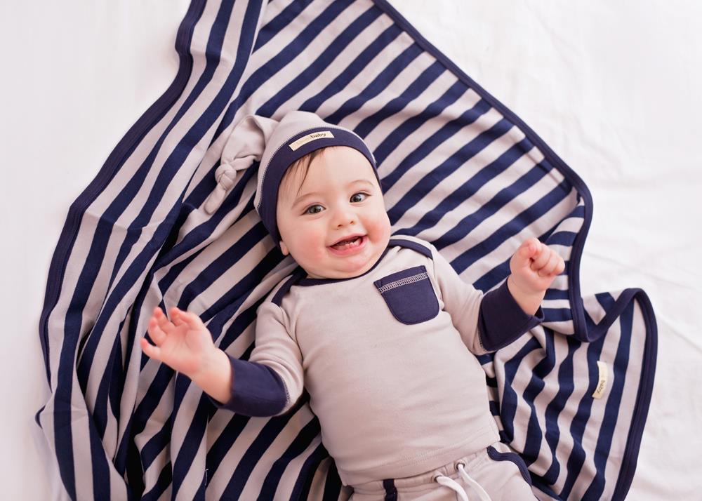 Child wearing Organic Swaddling Blanket in Navy/Light Gray Stripe.