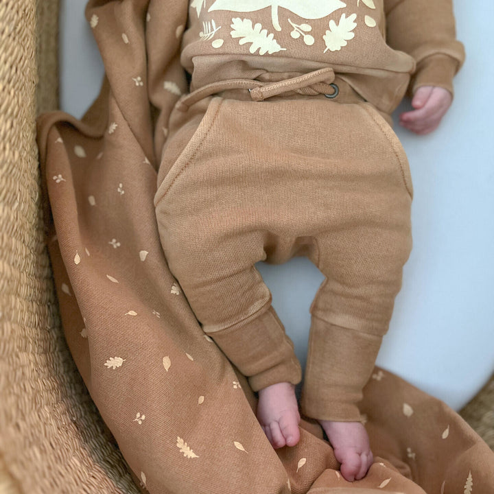 Child wearing Organic Cozy Blanket in Toffee Leaf.
