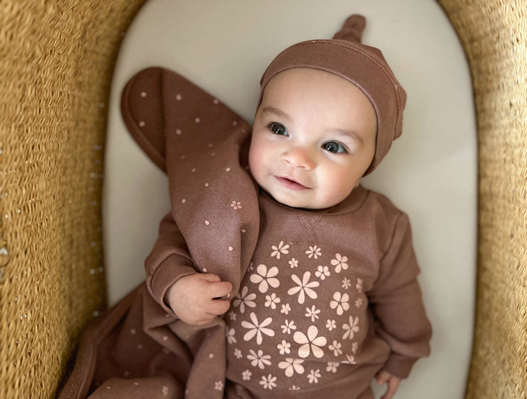 Child wearing Organic Cozy Top-Knot Hat in Rosewood Flower.