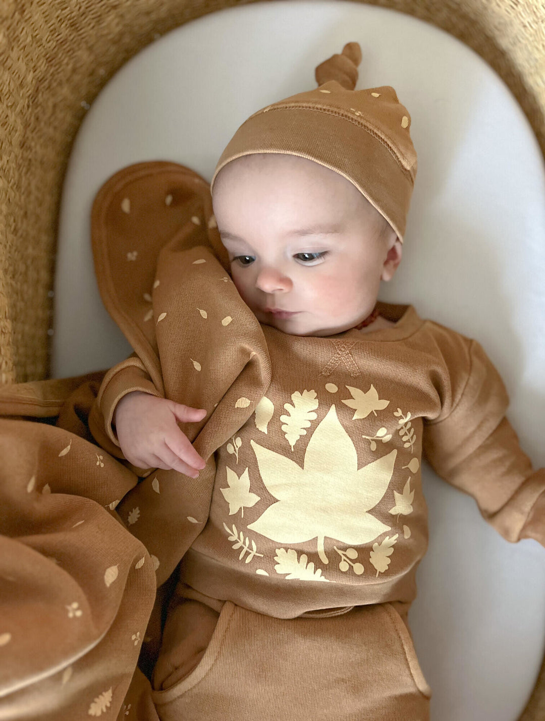 Child wearing Organic Cozy Top-Knot Hat in Toffee Leaf.