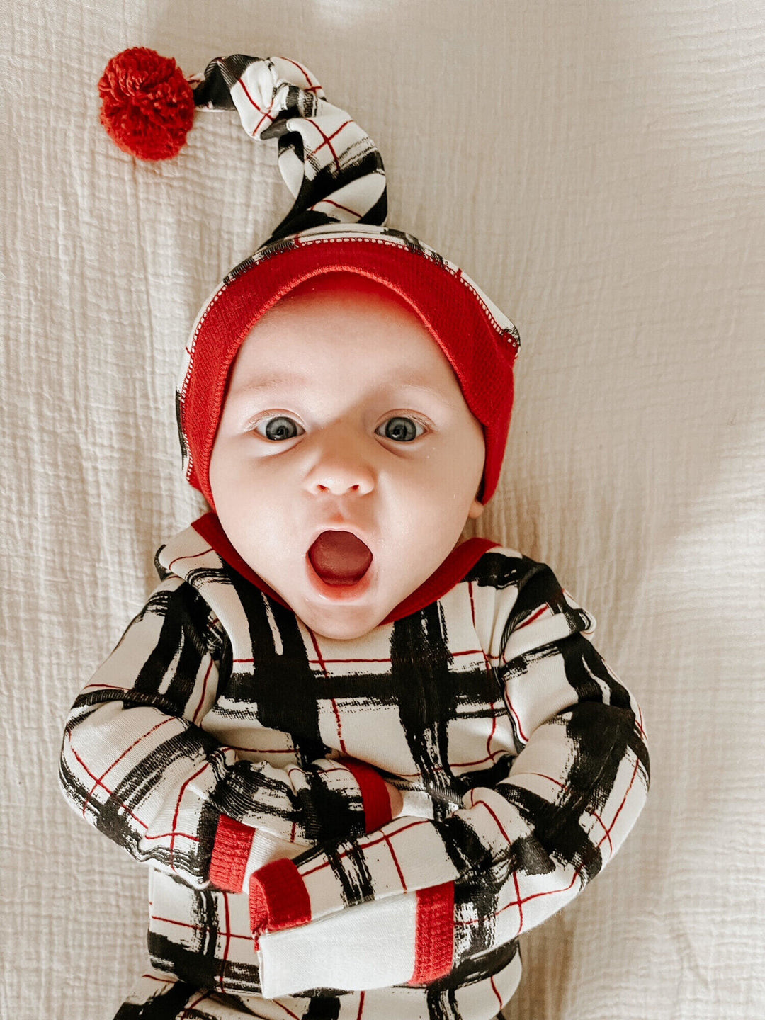 Child wearing Organic Holiday Footie & Cap Set in Christmas Day Plaid.
