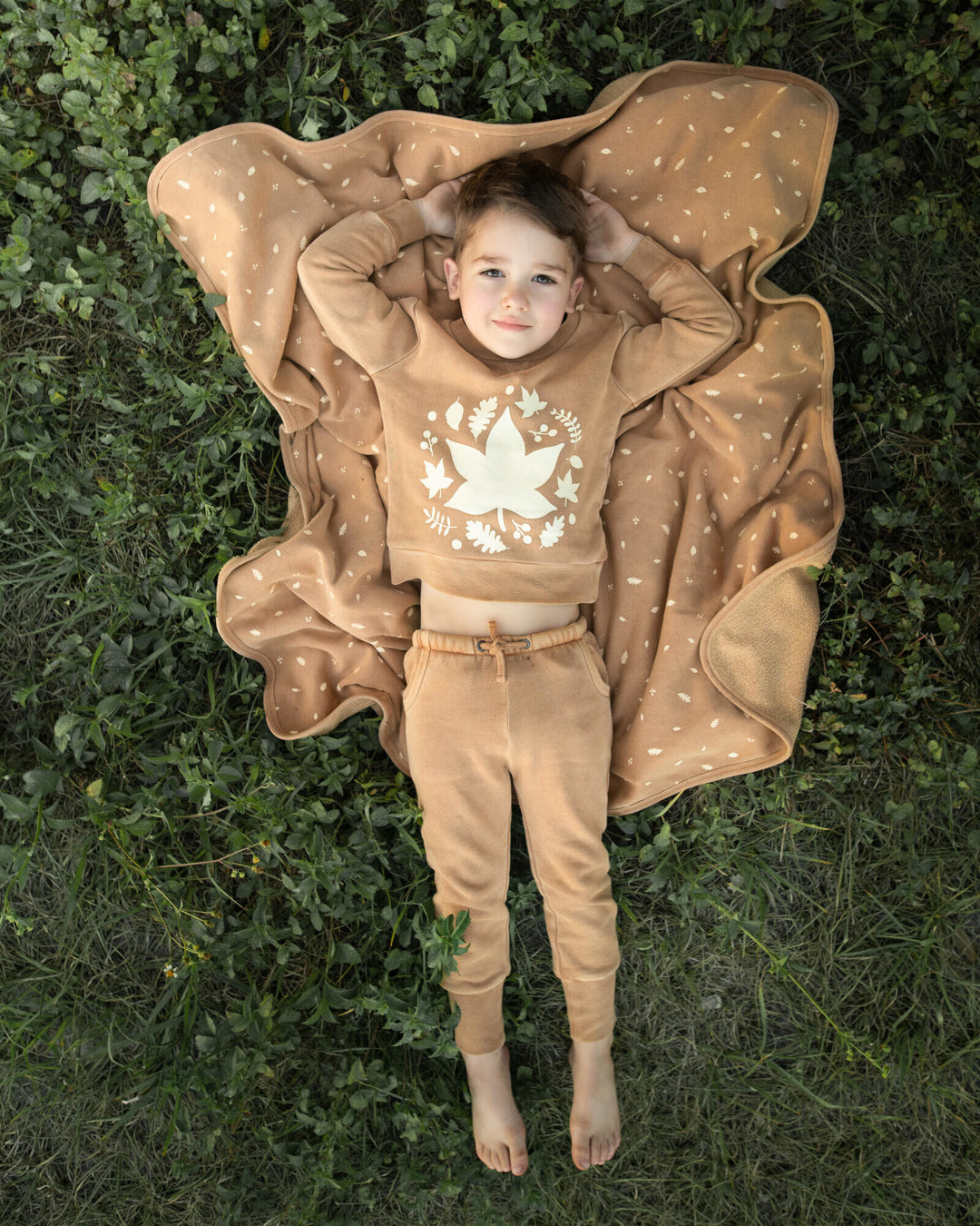 Child wearing Kids' Organic Cozy Graphic Sweatshirt & Jogger Set in Toffee Leaf.
