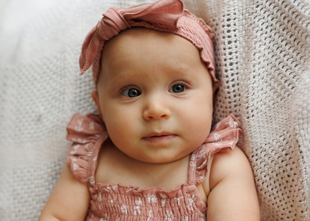Child wearing Organic Muslin Smocked Headband in Desert Rose.
