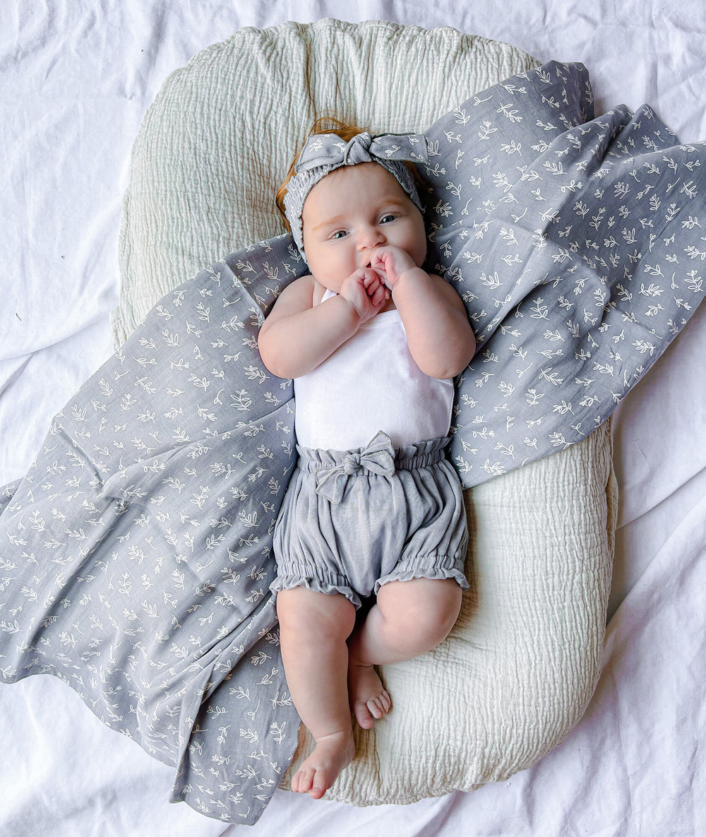 Child wearing Organic Muslin Blanket in Twilight Leaves.