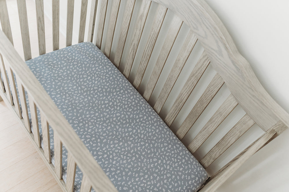Child wearing Organic Muslin Crib Sheet in Twilight Leaves.