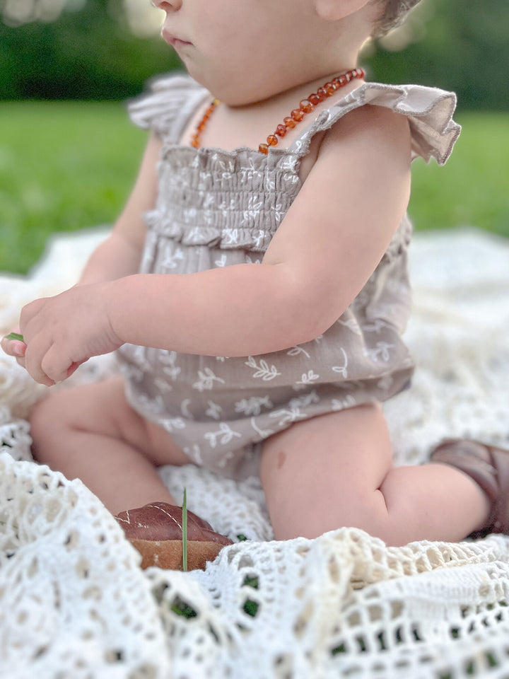 Child wearing Organic Muslin Sleeveless Bodysuit in Fawn Leaves.