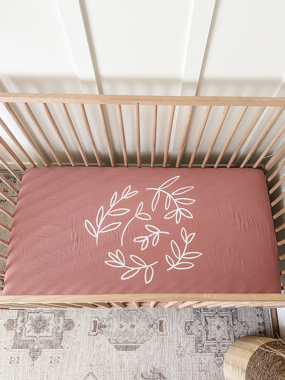 Child wearing Organic Muslin Crib Sheet 2-Pack in Desert Rose.