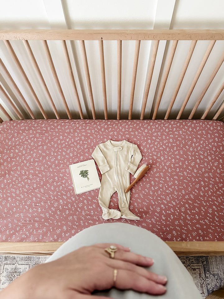 Child wearing Organic Muslin Crib Sheet 2-Pack in Desert Rose.