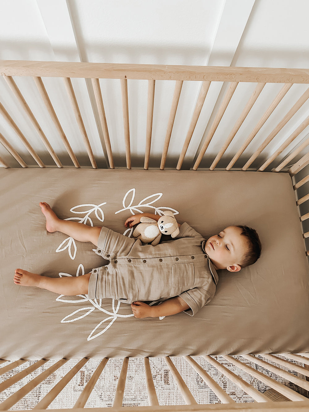 Child wearing Organic Muslin Crib Sheet 2-Pack in Fawn.