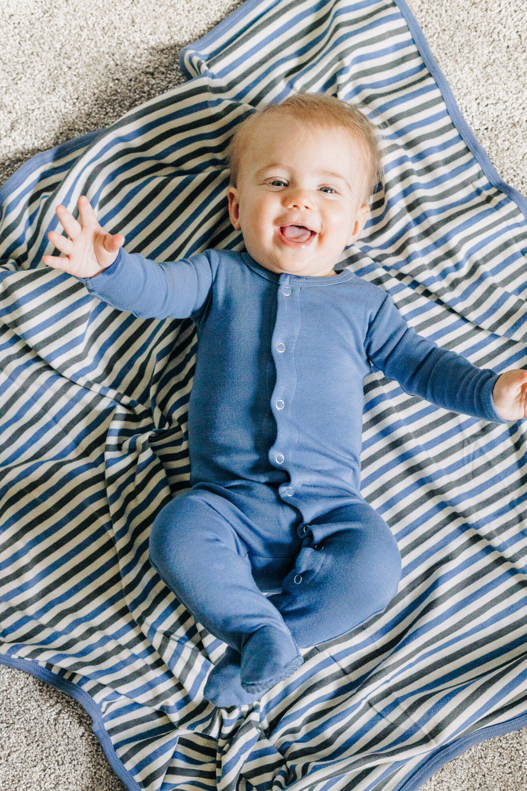Child wearing Organic Swaddling Blanket in Slate Stripe.
