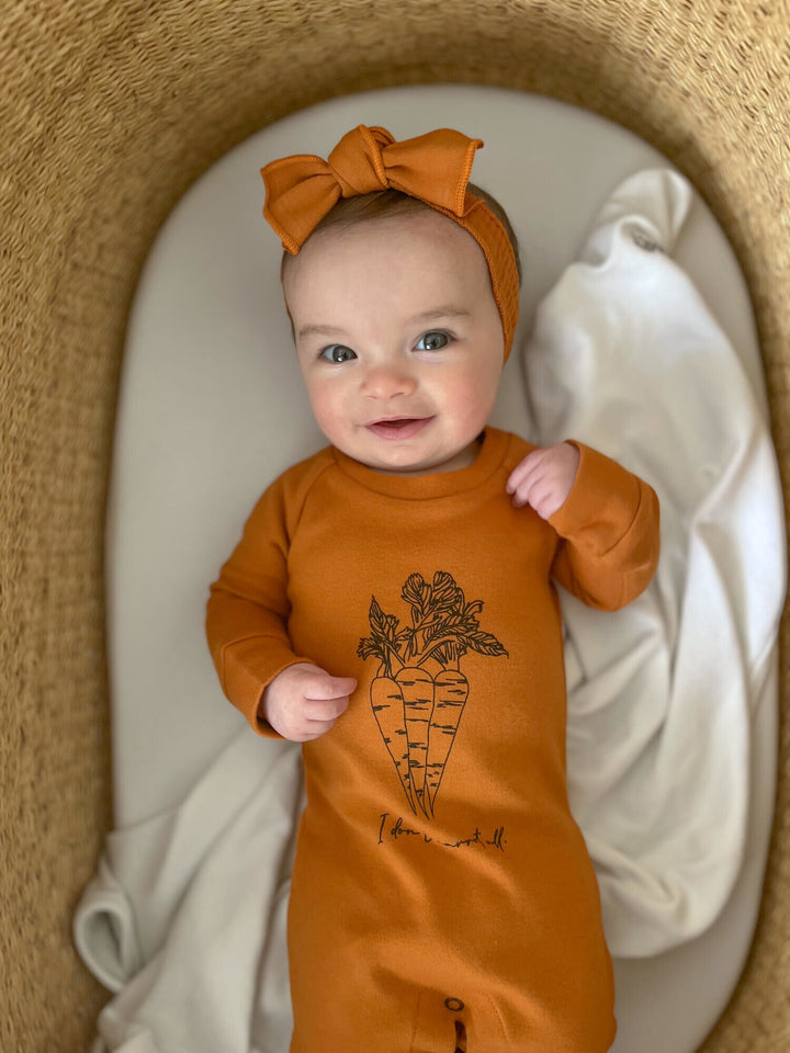 Child wearing Raglan Footie in Butternut Carrots.