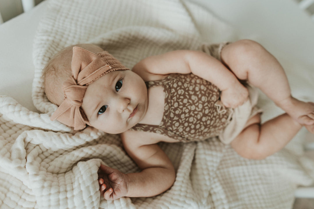 Child wearing Printed Criss-Cross Bodysuit in Latte Floral.