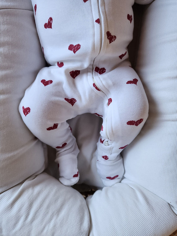 Child wearing Organic 2-Way Zipper Footie in Crimson Hearts.