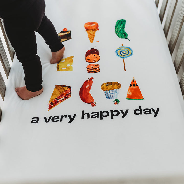 Child wearing Organic Crib Sheet 2-Pack in Happy Day.
