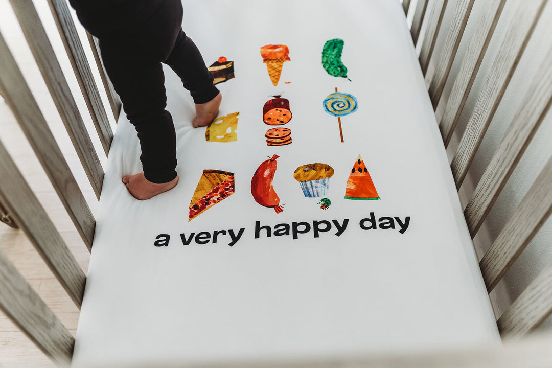 Child wearing Organic Crib Sheet 2-Pack in Happy Day.