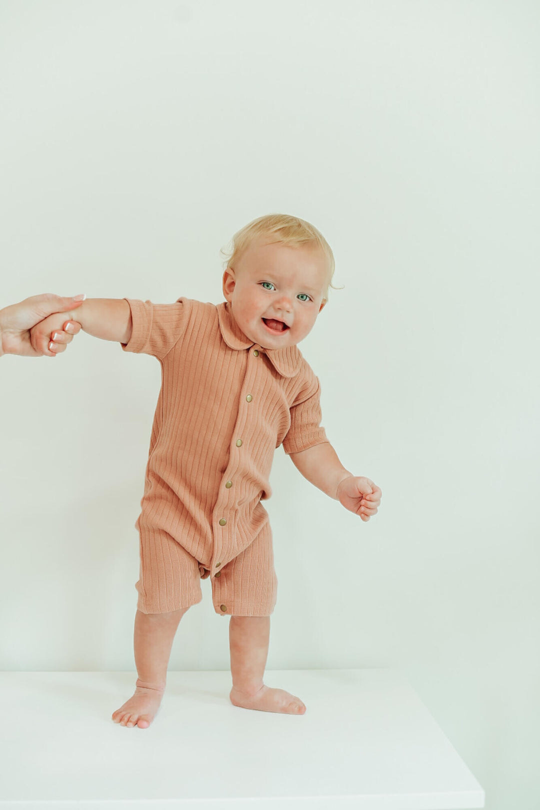 Child wearing Ribbed S/Sleeve Coverall in Adobe.