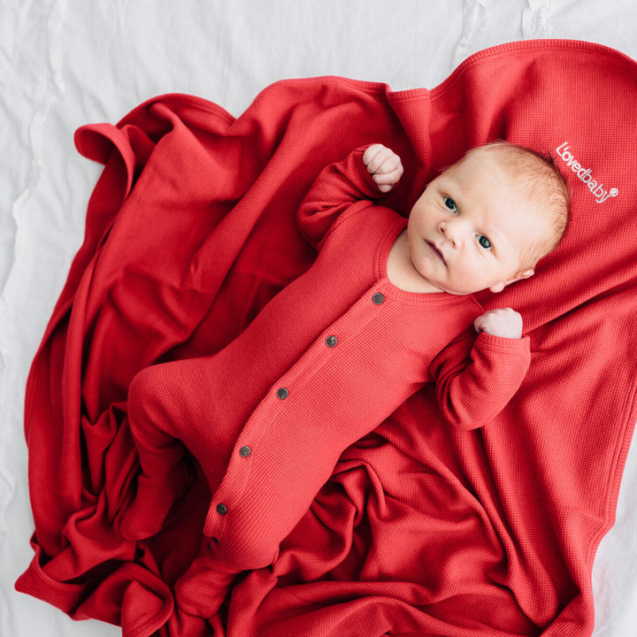 Child wearing Organic Thermal Swaddling Blanket in Cherry.