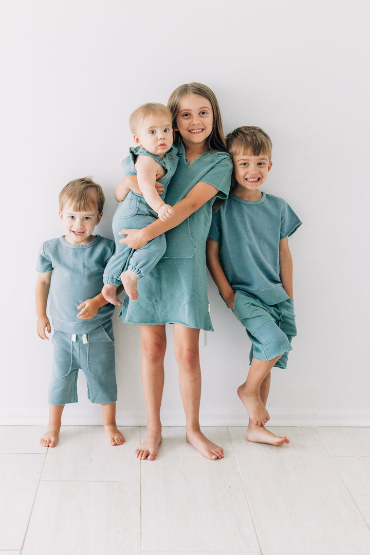 Siblings wearing matching French Terry outfits in Jade color. Centermost child is wearing the Kids' French Terry Hoodie Dress in Jade.