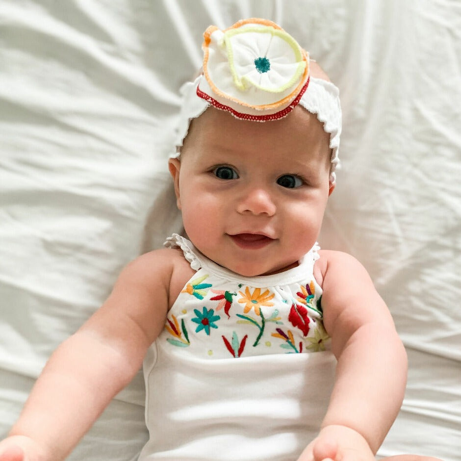 Child wearing Embroidered Flower Headband in White.