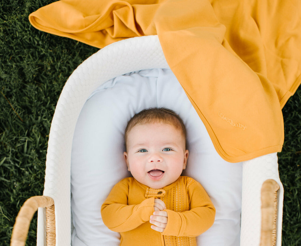 Child wearing Organic Swaddling Blanket in Tangerine.