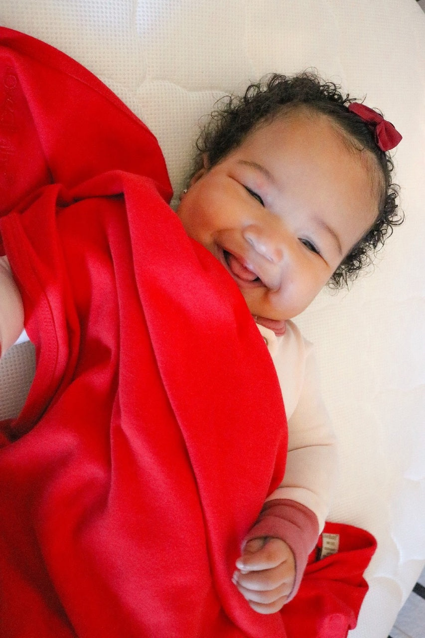 Child wearing Organic Swaddling Blanket in Chili Pepper.