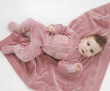 Child wearing Organic Velour footie in mauve.