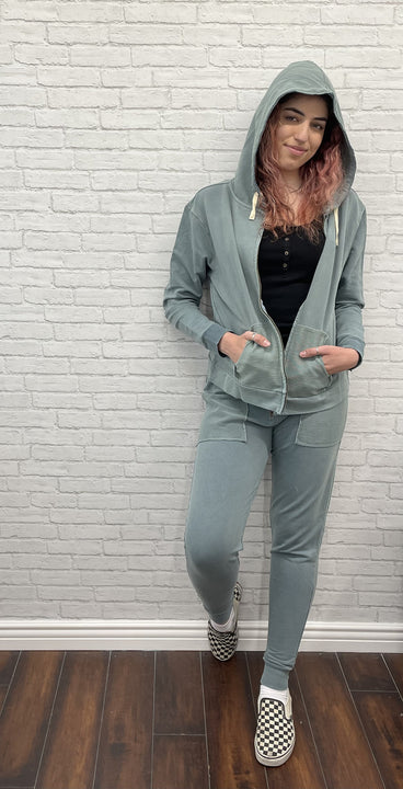 Woman wearing Jade colored jacket and jogger. 