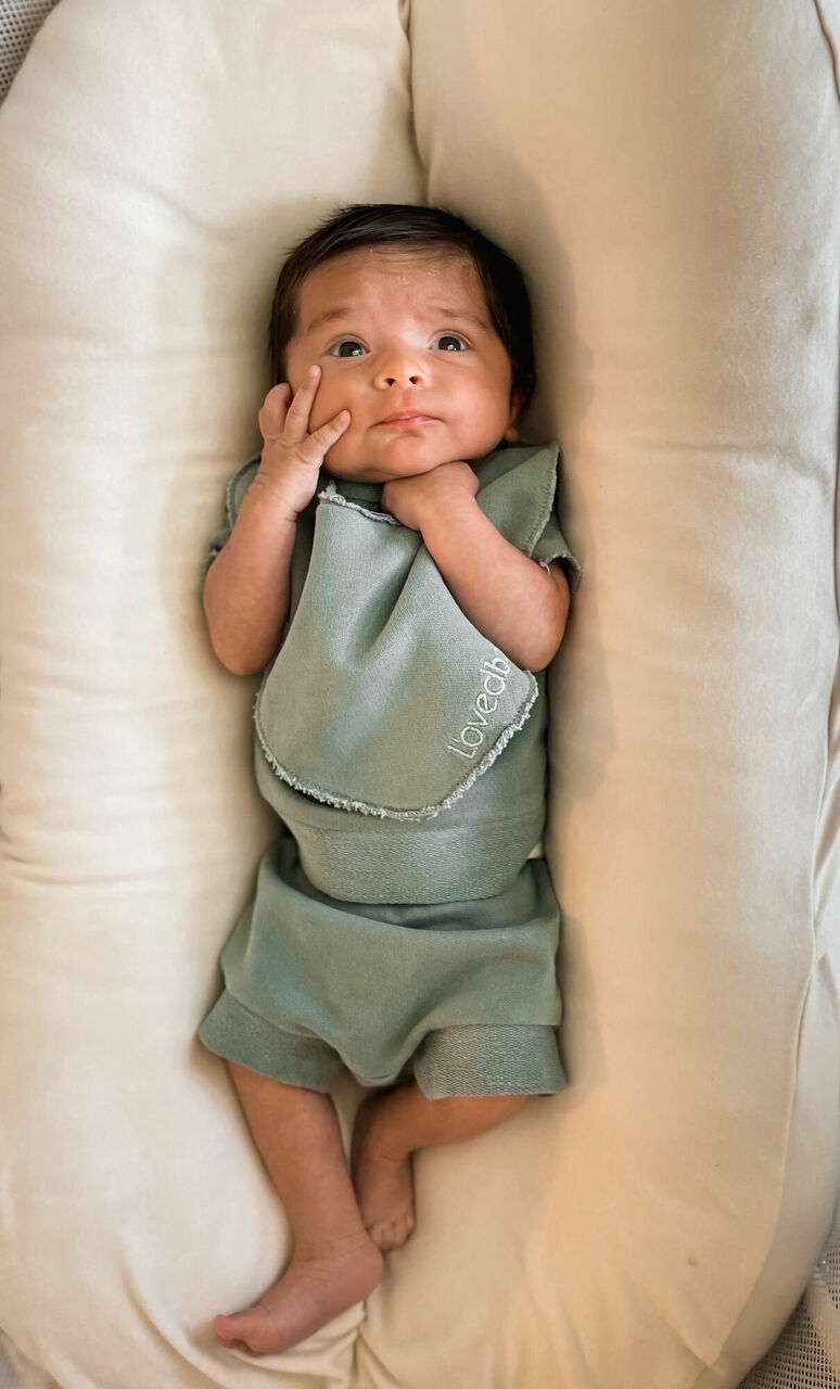 Child wearing French Terry Reversible Bib in Jade.