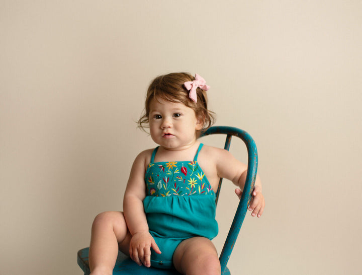 Child wearing Embroidered Criss-Cross Bodysuit in Teal Floral.