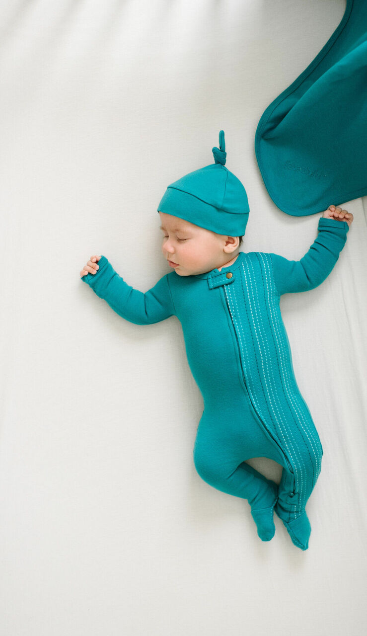 Child wearing Embroidered Zipper Footie in Teal Dash.