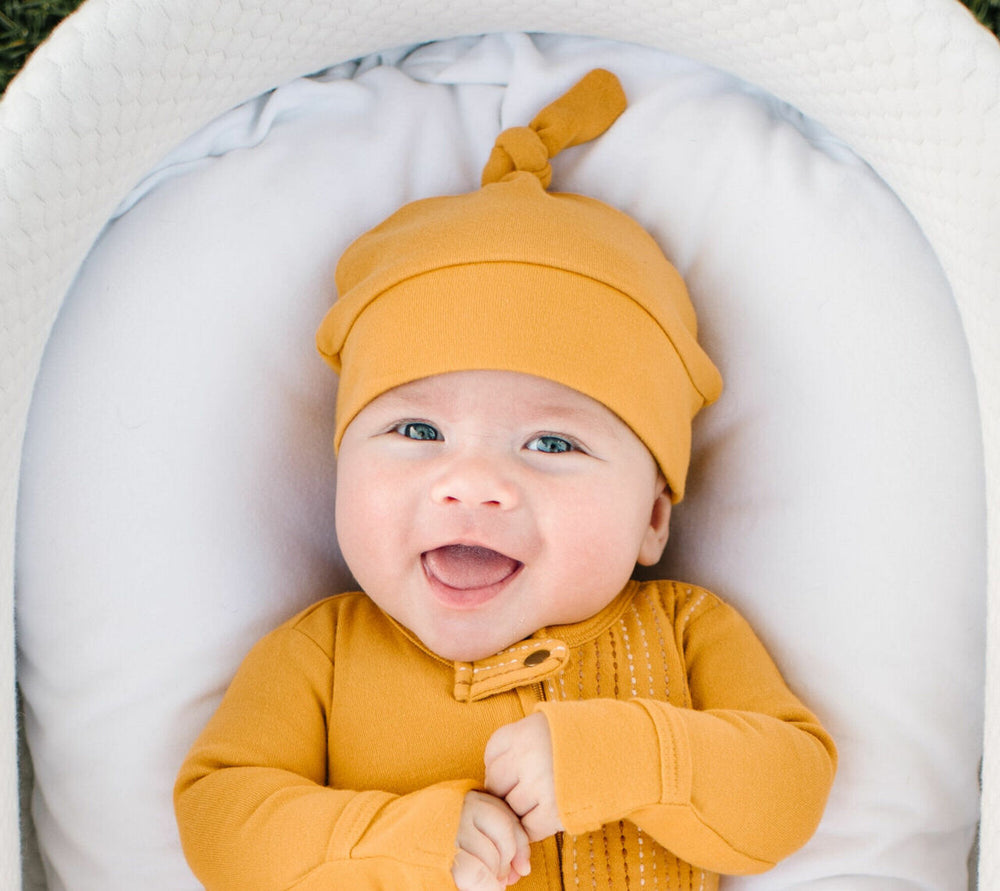 Child wearing Organic Banded Top-Knot Hat in Tangerine.