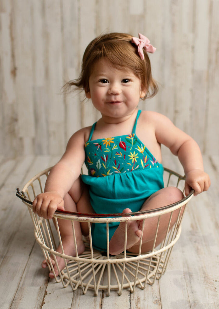 Child wearing Embroidered Criss-Cross Bodysuit in Teal Floral.