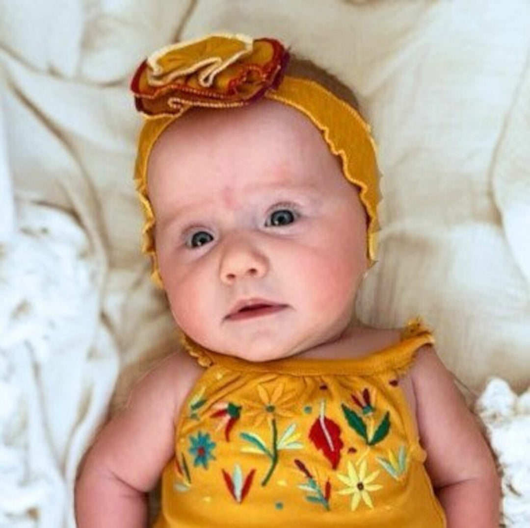 Child wearing Embroidered Flower Headband in Tangerine.
